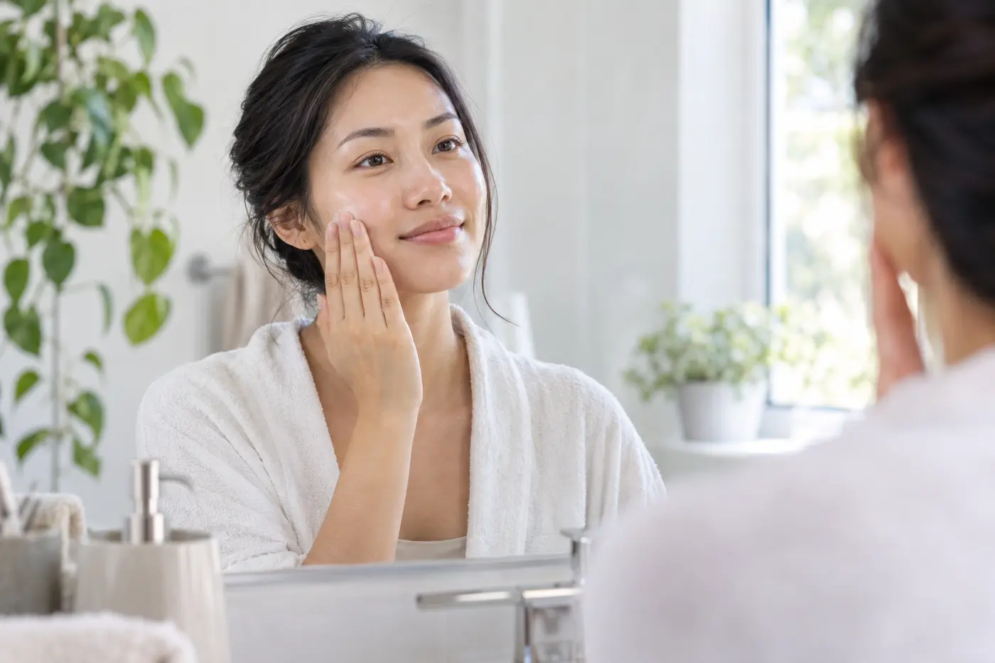 Woman gently pressing toner onto her cheek in a calm bathroom setting
